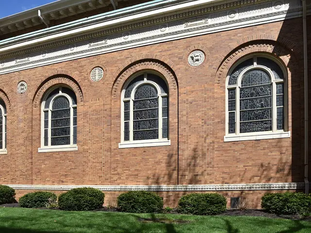 Exterior side wall of St. Joseph Catholic Church in Dayton, Ohio, showing brick arched windows with stained glass.