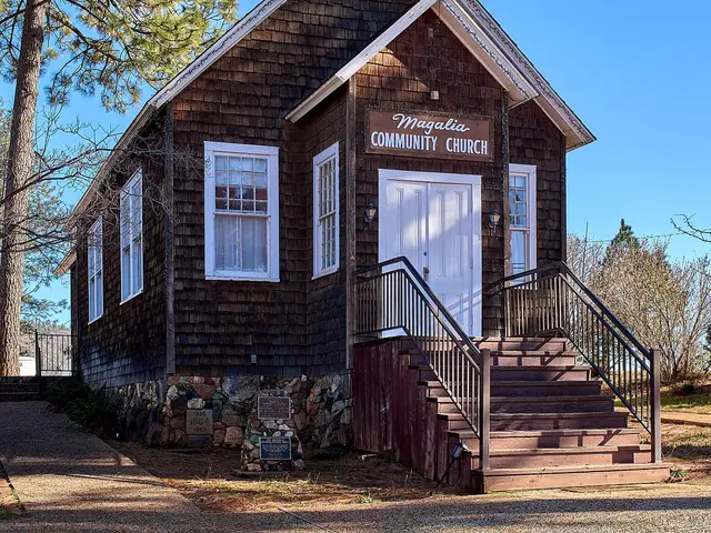 The exterior of a historic white wooden church building with a small steeple.