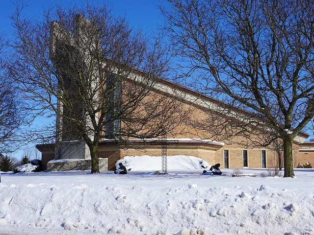 The exterior of a brick church building with a steeple, photographed in winter.