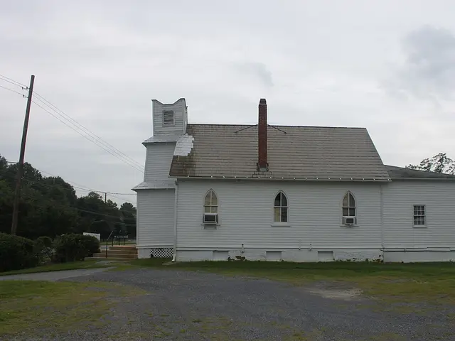 The exterior of a small white wooden church building with a steeple.