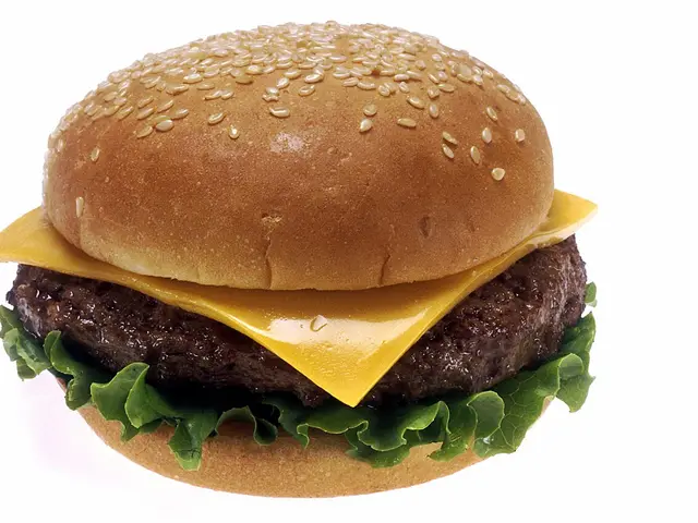 A cheeseburger with lettuce, tomato, and a sesame seed bun on a plate.
