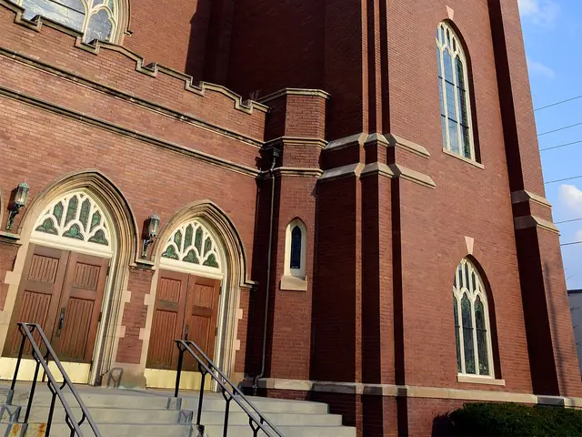 Exterior of Zion Evangelical United Church of Christ, a brick building with a stone bell tower and arched stained-glass windows.