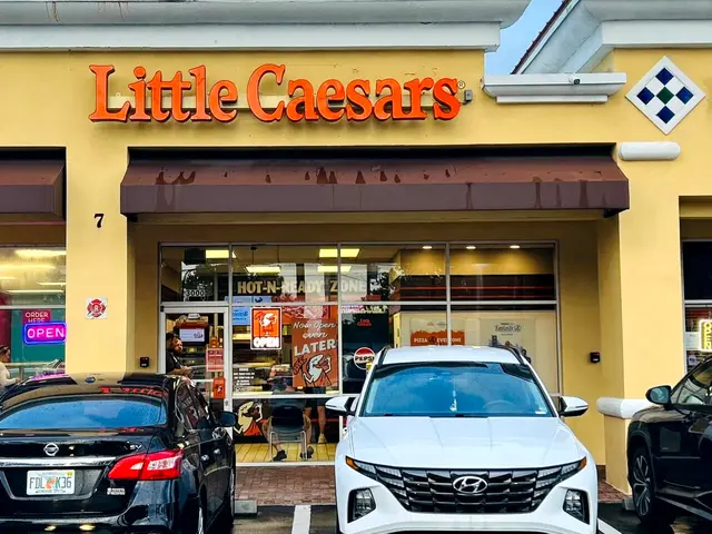The storefront of a Little Caesars pizza restaurant with branding and a walk-up window visible.