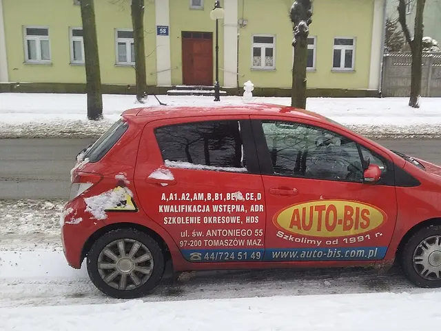 A red driving-school car marked 'Auto-Bis' parked on a snowy street in Tomaszów Mazowiecki, Poland.