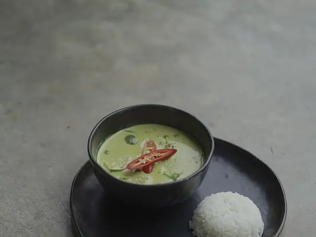 A bowl of Thai green curry served with rice.