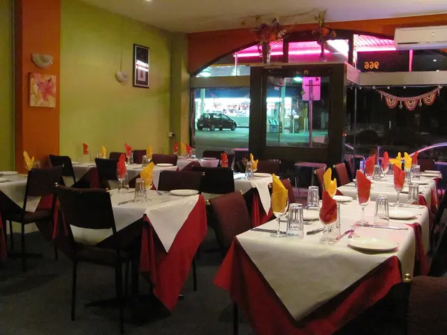 The dining room interior of an Indian restaurant with tables set for service.