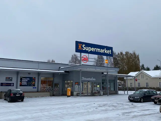 K-Supermarket storefront with a large blue and yellow sign, cars parked outside in winter