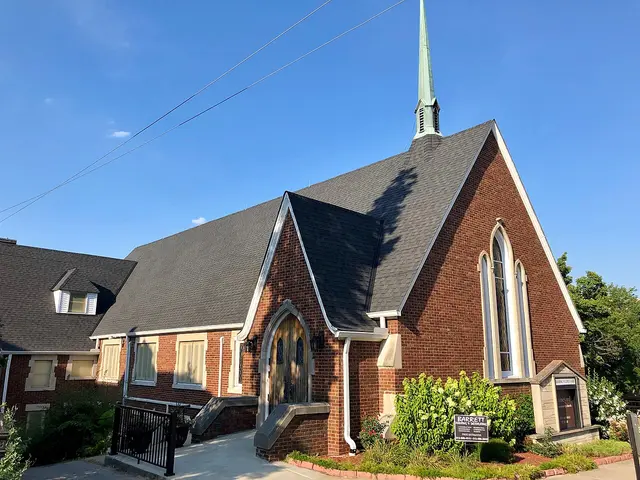 Exterior of Vineyard Community Church, a red brick building with a white steeple, in Aurora, Indiana.