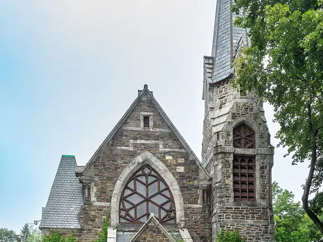 The exterior of a stone church building with a steeple.
