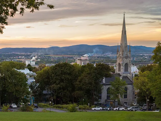 Stone Gothic Revival spire of Chalmers-Wesley United Church rising above trees, viewed across the Quebec City skyline at dusk.