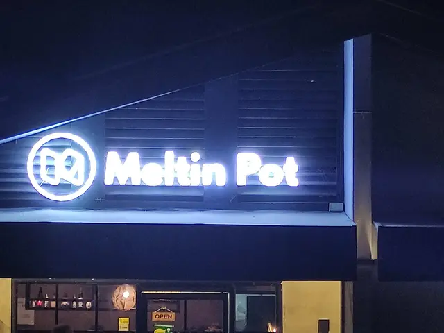 Nighttime exterior of the Meltin Pot restaurant with an illuminated sign.