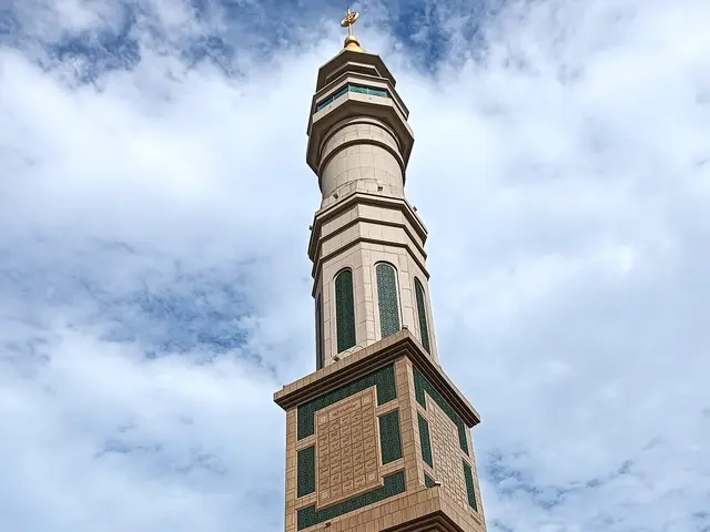A mosque minaret against a cloudy sky