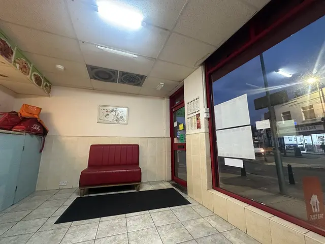 Customer seating area of Summer Palace restaurant in Gillingham, England, seen through the storefront window.
