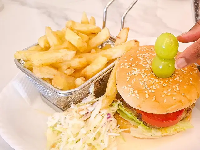 A beef burger with french fries, salad, and sauce on a tray.