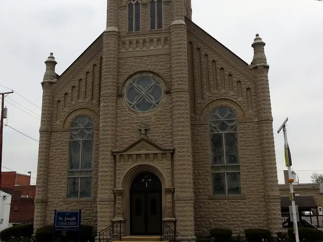 Exterior of Saint Joseph Catholic Church in Galion, Ohio, a stone church with a tall square bell tower topped by a cross.