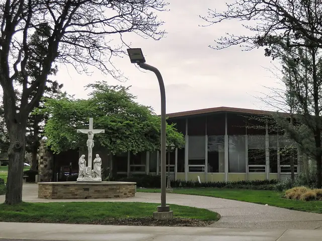 Exterior of Holy Cross Chaldean Catholic Church in Farmington Hills, Michigan, a low modern building with a crucifixion statue in the courtyard.