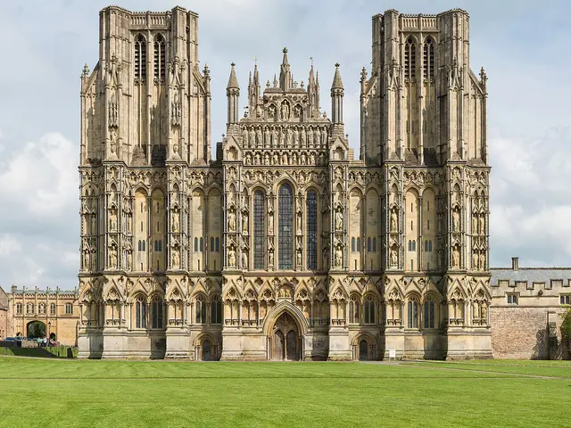 West front facade of Wells Cathedral in England, showing its two towers and rows of carved stone statues.