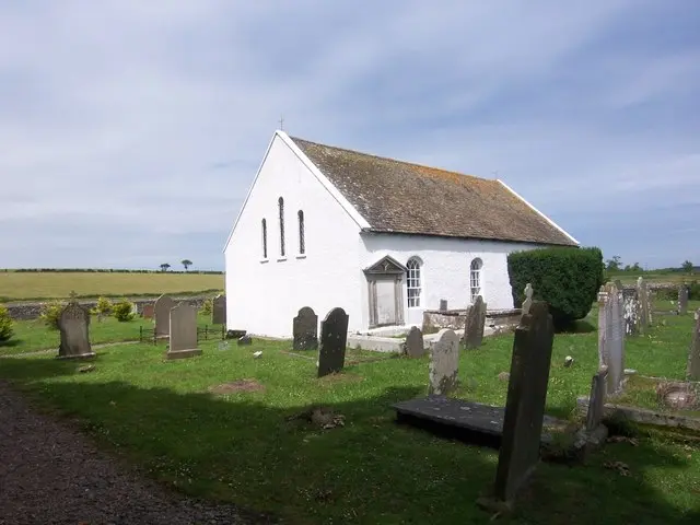 Exterior of Lisbane Roman Catholic Church, a small whitewashed church surrounded by a graveyard.