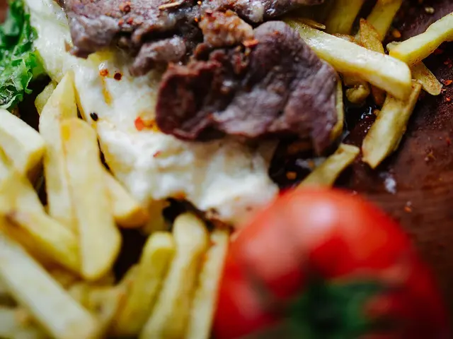 Grilled meat slices with mashed potatoes, fries and tomatoes on a restaurant plate.