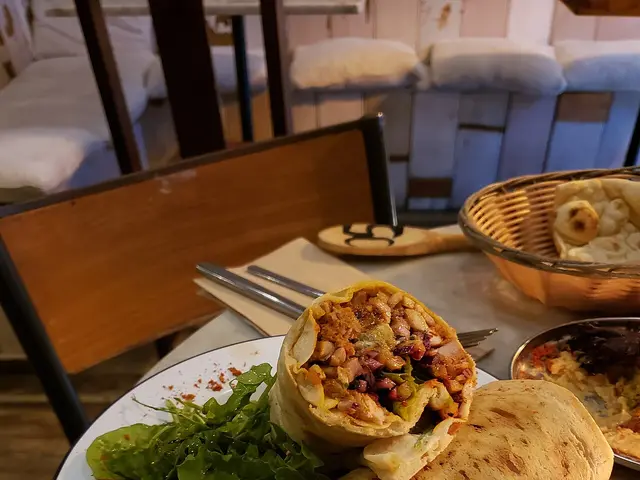A chicken shawarma wrap served with herbs and a yogurt sauce.