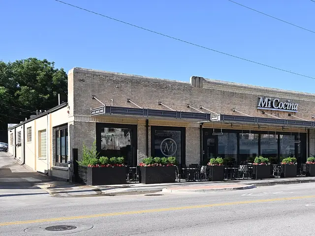 Exterior of a restaurant storefront with outdoor planters along the sidewalk.