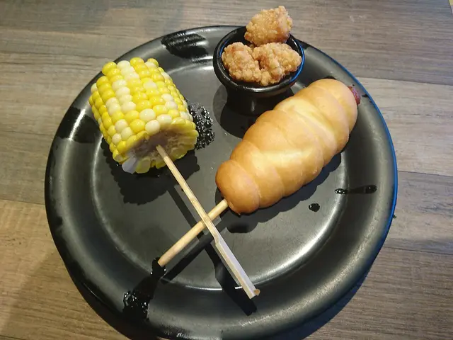 A corn dog served with a side of corn.