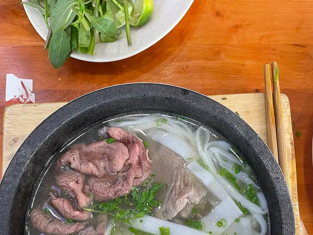 A bowl of Vietnamese pho noodle soup served in a stone bowl.