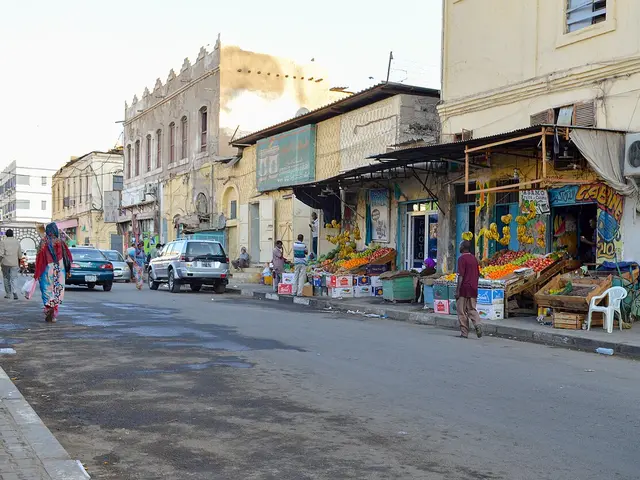 A street-side grocery and fruit stall in Djibouti City, with produce displayed under an awning along a row of colonial-era buildings.