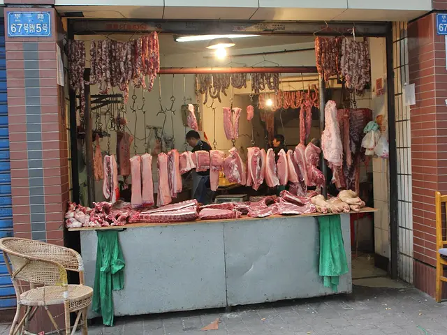 A butcher's storefront stall in Chongqing with cured sausages and cuts of meat hanging above a display counter.