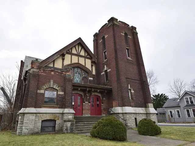 Red-brick Church of Christ with a tall corner bell tower and Tudor-style gable at the entrance.