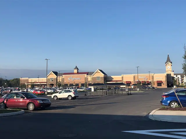 Wegmans supermarket exterior seen across a parking lot, with a peaked entrance and clock tower