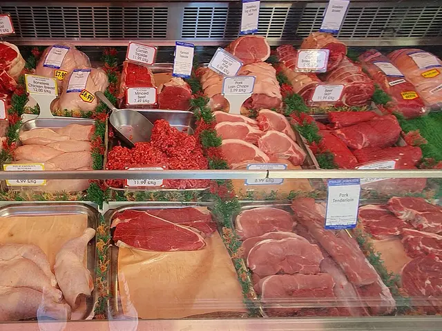 A butcher shop's glass display case filled with labeled cuts of beef, pork, and chicken.