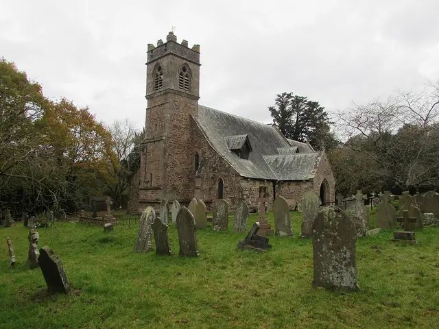 The exterior of a stone village church with a square tower.