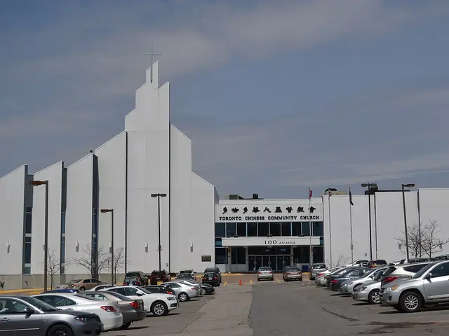 White multi-peaked Christian church building with a cross atop its highest gable, signed Toronto Chinese Community Church, cars parked in front