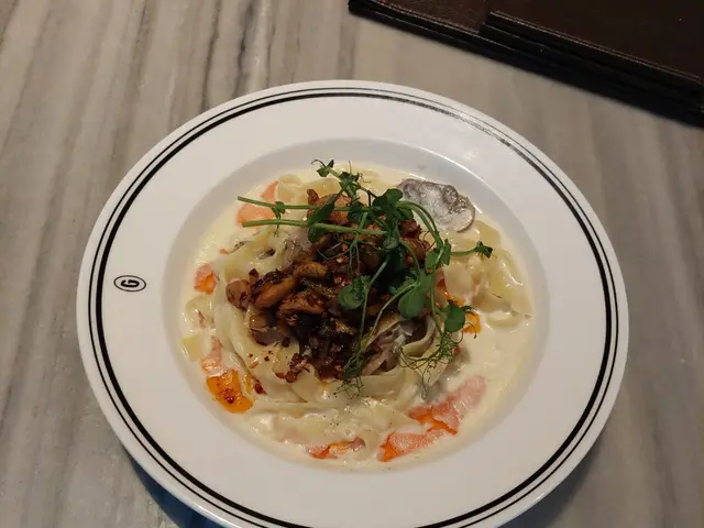 A plate of pasta served on a white plate at a restaurant table.