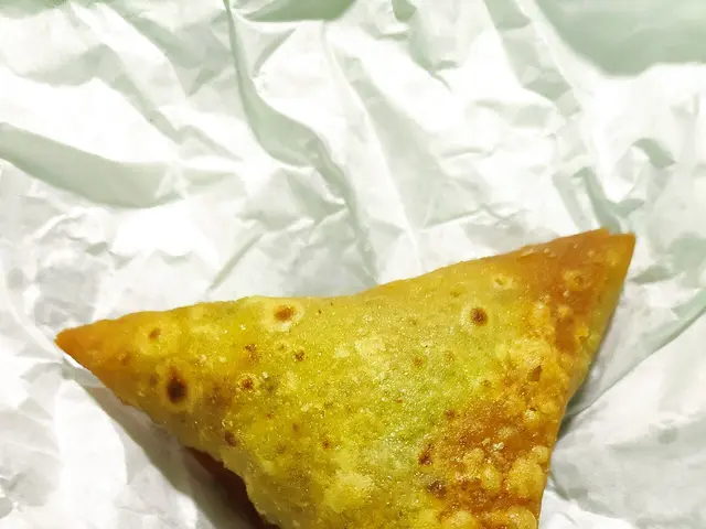 A fried Indian samosa, a triangular pastry filled with spiced potatoes.