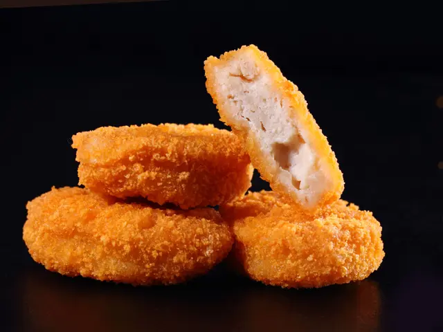 Four chicken nuggets, one half-eaten, against a dark background.