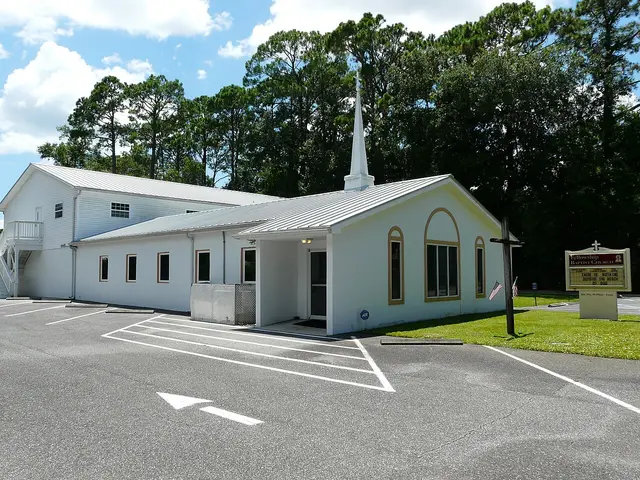 Small white fellowship church building with a steeple and arched windows on a quiet street in Apalachicola, Florida.