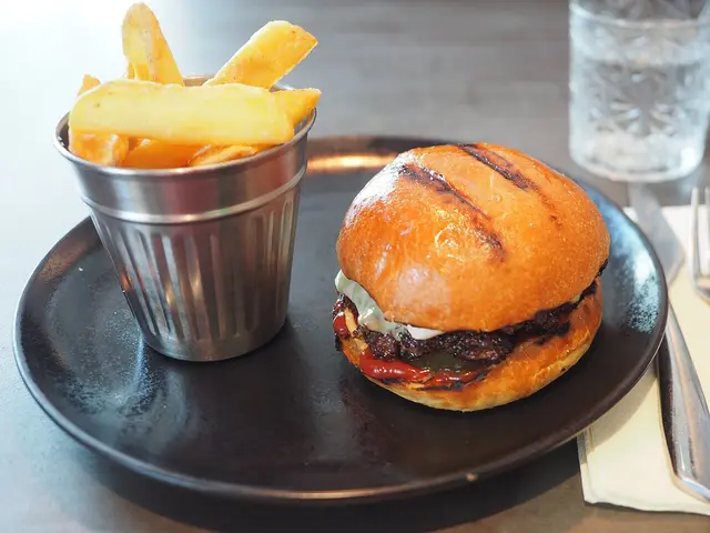 A smashed burger with fries served at a restaurant table.
