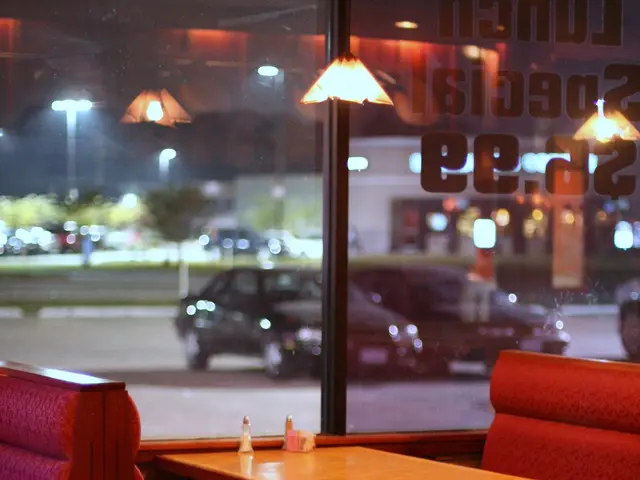A cushioned restaurant booth with a table, chairs and place settings.
