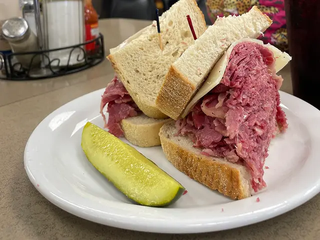 A corned beef sandwich with Swiss cheese served on a plate at a restaurant.