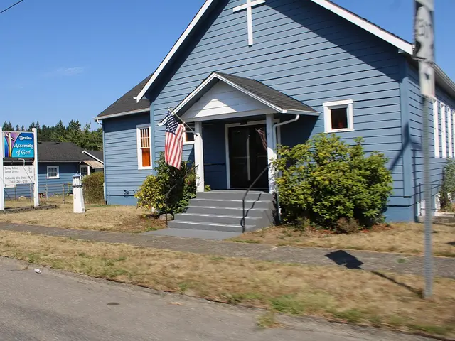 White wood-sided Assembly of God church in Tenino, Washington, with a green metal roof, small bell tower and a Thanksgiving dinner yard sign.