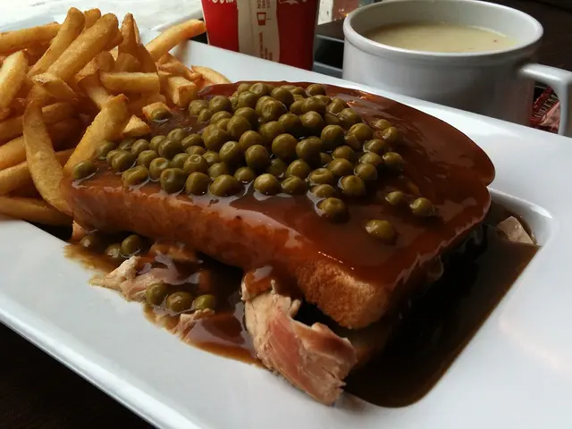 A hot chicken sandwich served with fries and sides on a restaurant table.