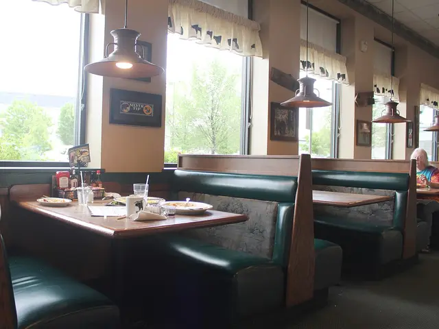 Green vinyl booths and wood trim inside a diner restaurant, with dishes left on a table.
