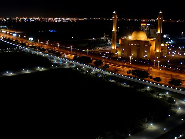 A mosque illuminated at night beside a city skyline