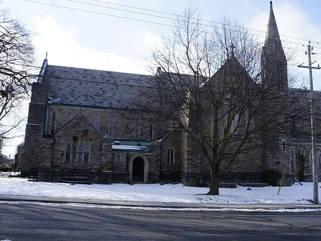The exterior of a stone church building with a tower, photographed in winter.