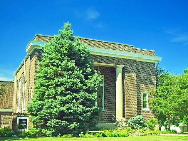 Exterior of Newtown Community Church, a brick building with a white-columned entrance, in Newtown, Indiana.