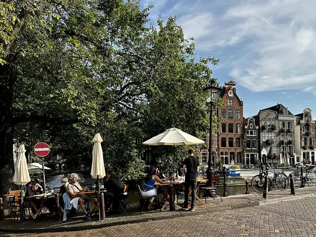 A sidewalk cafe with outdoor tables on Herengracht canal in Amsterdam.