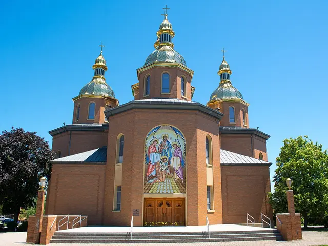 Red brick Ukrainian Catholic cathedral with three gold onion domes and a large mosaic of Christ above the entrance