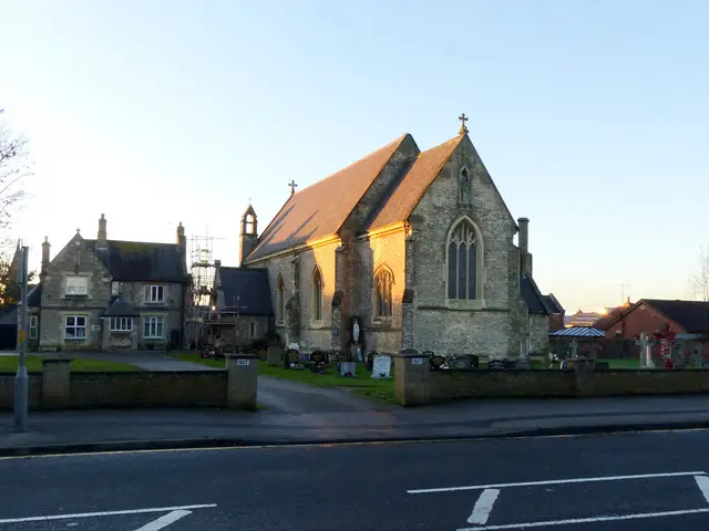 Exterior of the Roman Catholic parish church of St Mary in Carlton, a stone church with a bell turret, seen from the road at sunset.